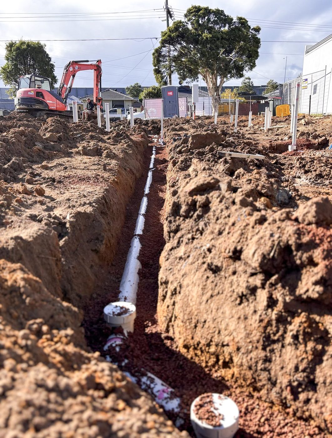 Deep trench with new drainage pipe being installed on site.