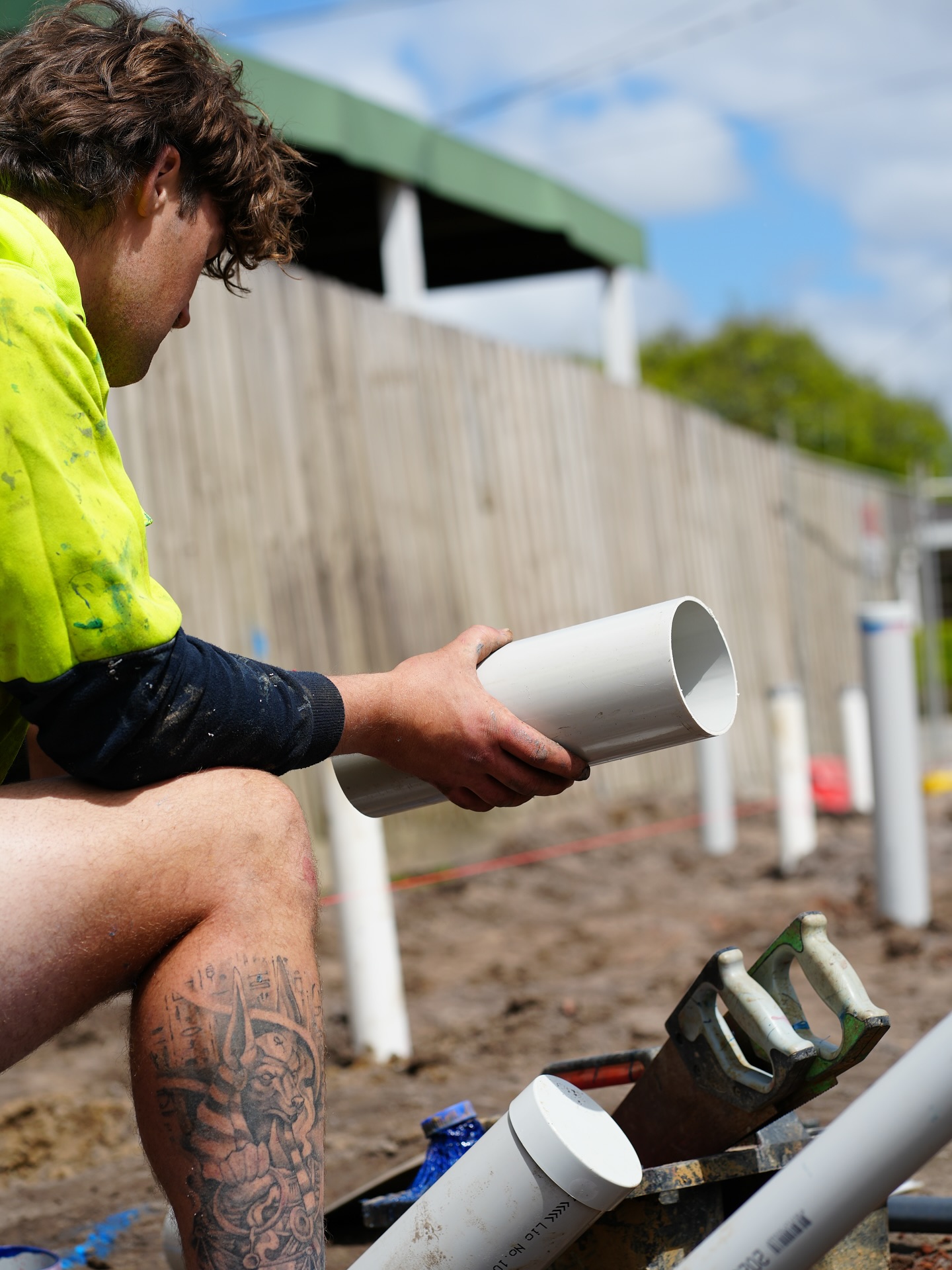 Worker cutting PVC pipe to length on site.