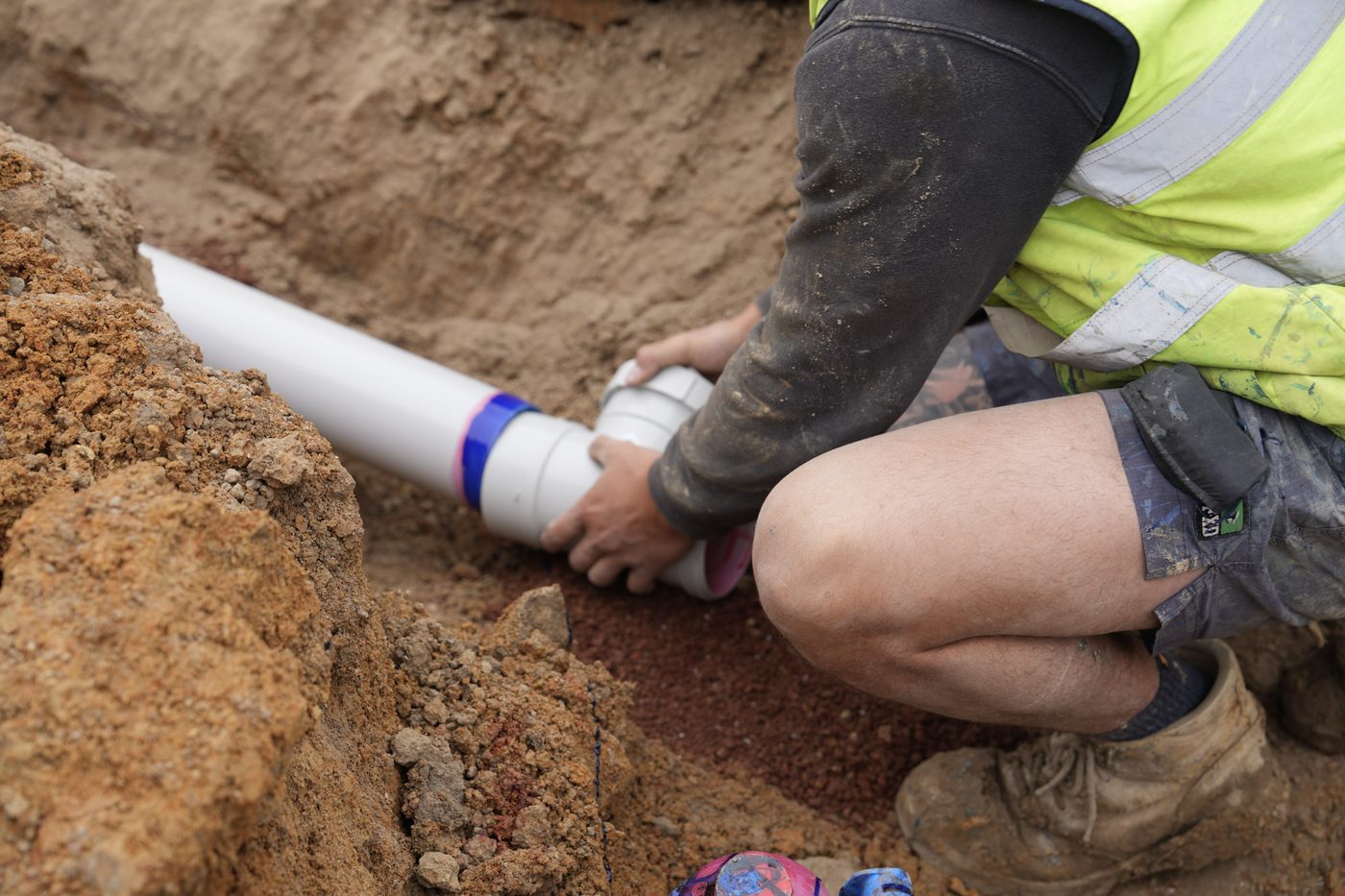 Solvent-welding PVC pipe joints in the trench before backfill.