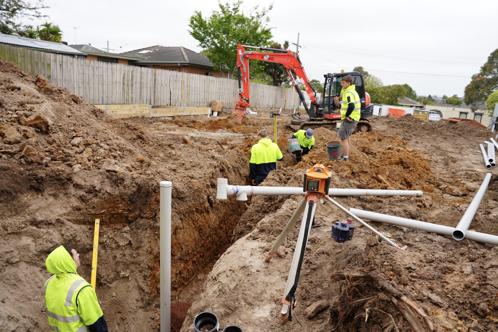 Open excavation with the crew laying drainage pipe in the trench.